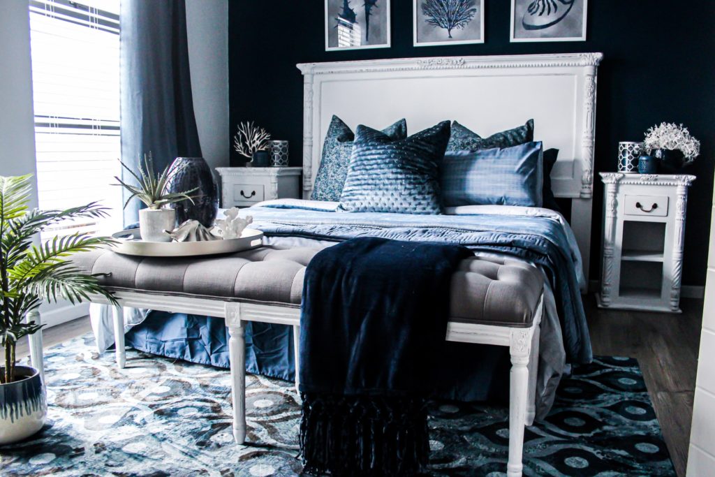 a black and white bed with a white pillow and a black chair