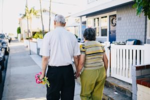 a man and woman holding hands and walking down a sidewalk