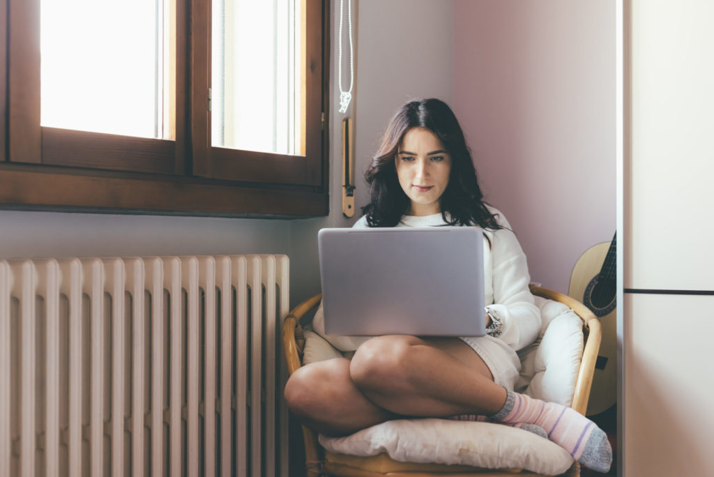 Young woman indoor at home sitting armchair using computer